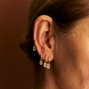 model wearing stacked Alphabet diamond charm earrings